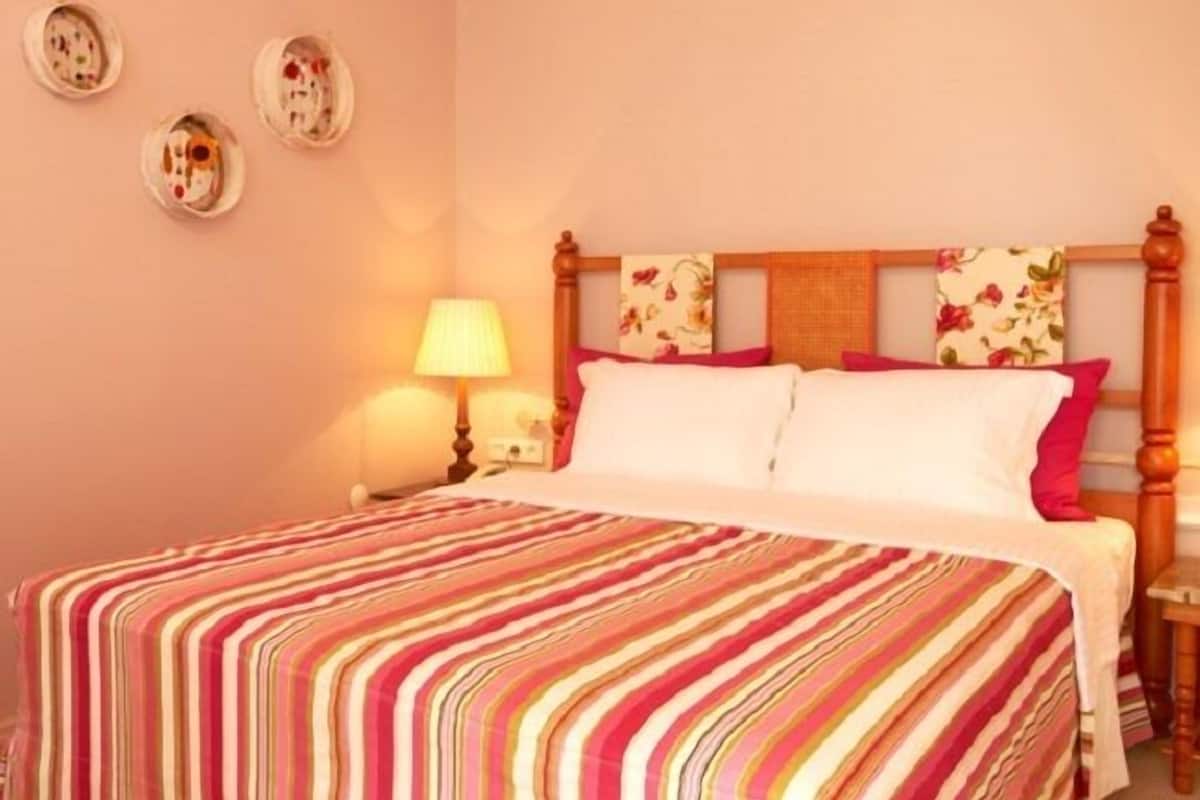 A hotel room with a bed, a nightstand, a lamp, and three wall-mounted plates.