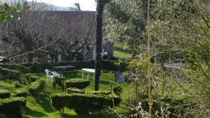 Un jardín bien cuidado con setos ordenados, una mesa de picnic y algunas sillas.