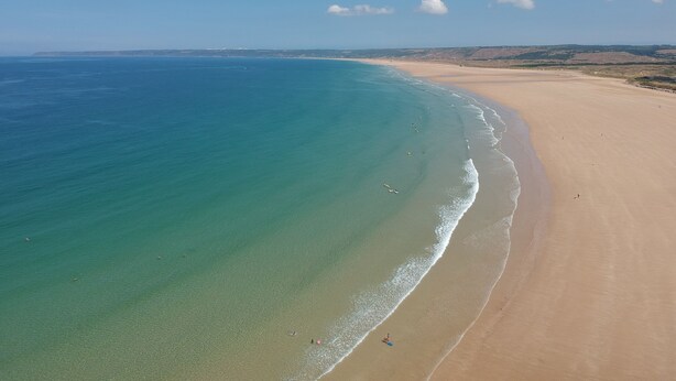 Una playa con aguas cristalinas y una extensa orilla de arena.