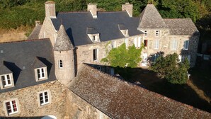 Un edificio de piedra con varias chimeneas, una torre y un tejado inclinado.