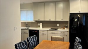 A modern kitchen with white cabinets, a black refrigerator, and a wooden dining table with patterned chairs. - Beautiful Mountain Getaway in Breckenridge, CO (Breckenridge)