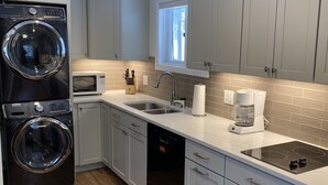 A modern kitchen with grey cabinets, a built-in washer and dryer, a microwave, a sink, and a coffee maker. - Beautiful Mountain Getaway in Breckenridge, CO (Breckenridge)