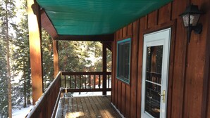 A wooden deck with a green awning, a door with a glass panel, and a metal lantern. - Beautiful Mountain Getaway in Breckenridge, CO (Breckenridge)