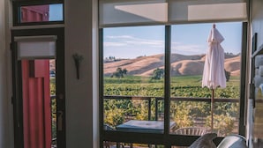 A bedroom with a large window overlooking a vineyard. - Geneseo Inn (Paso Robles)