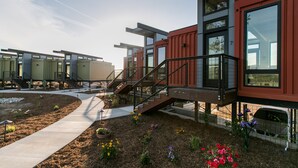 A modern building with a unique shipping container design, featuring a central staircase and a pathway leading to the entrance. - Geneseo Inn (Paso Robles)