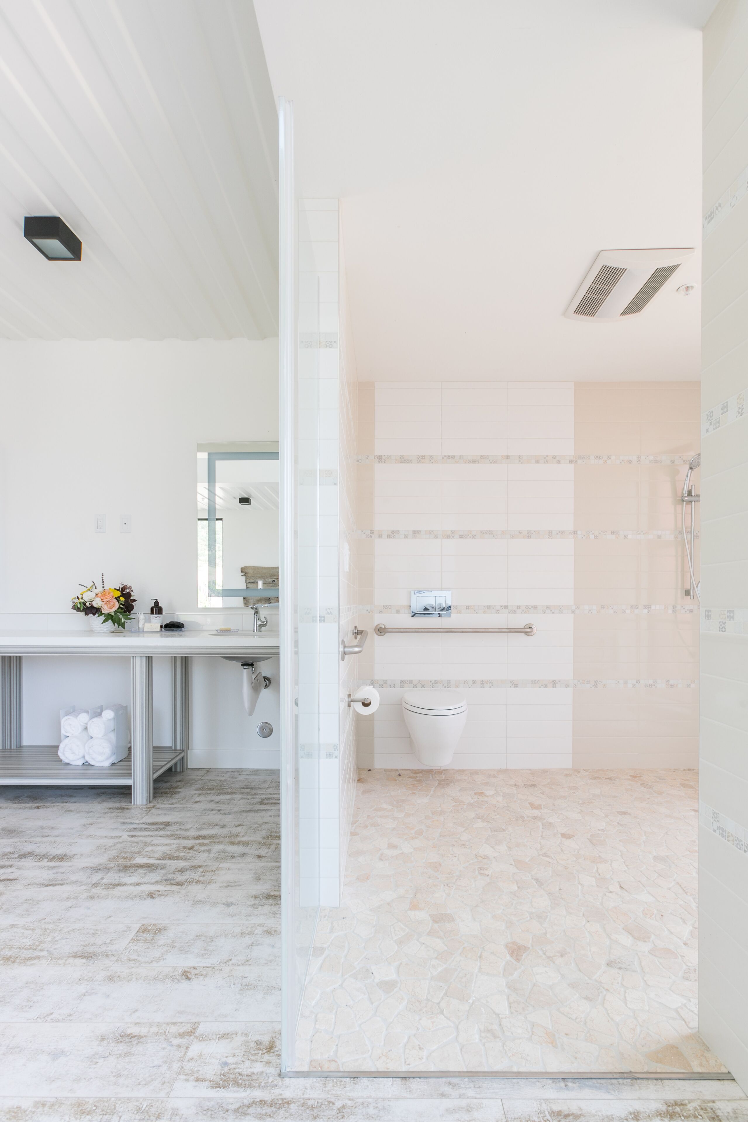A modern bathroom with a shower, toilet, and sink.