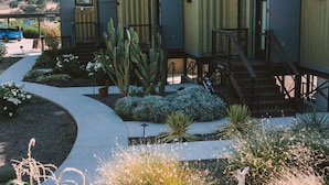 A modern building with a courtyard featuring a cactus, a pathway, and a seating area. - Geneseo Inn (Paso Robles)