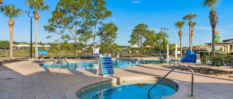 A pool area with a hot tub, lounge chairs, and palm trees.