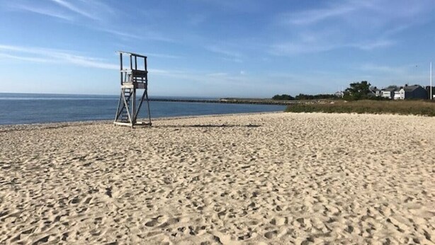 Ein Sandstrand mit einem Rettungsturm und einem strahlend blauen Himmel.