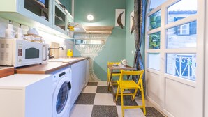 Une cuisine compacte équipée d’un lave-linge, d’un four à micro-ondes et d’un plan de travail en bois.