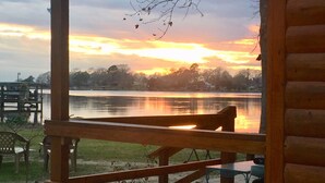 A wooden deck with a bench overlooking a calm lake during sunset. - Waterfront Cabin #1, Onalaska, Lake Livingston, Texas (Onalaska)