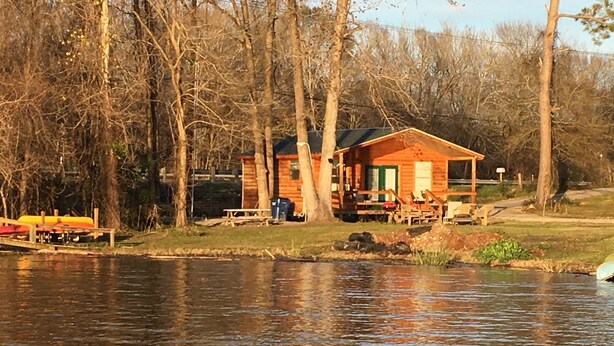 A cabin by a lake with a dock, picnic table, and outdoor seating. - Waterfront Cabin #1, Onalaska, Lake Livingston, Texas (Onalaska)