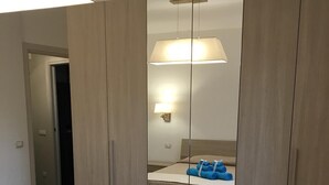 A bedroom with a bed, a wardrobe, and a mirror.