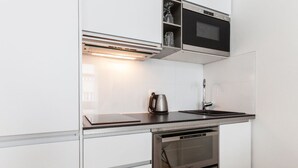 Una cucina moderna con forno a incasso, bollitore e forno a microonde.