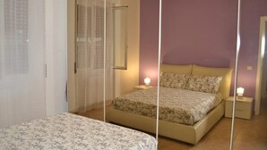 Quarto com cama, mesa de cabeceira e espelho.