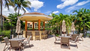 An outdoor patio with hexagonal tiles, a covered bar area, and multiple tables and chairs.