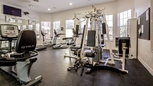 A gym with cardio machines, weightlifting equipment, and a treadmill.