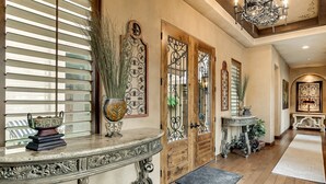 A hallway with a wooden floor, decorative doors, and a console table with a vase and books. -  Heated resort pool , jacuzzi, out door sound system, secluded courtyard.<br> (Scottsdale)