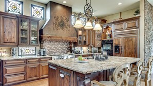 A spacious kitchen with wooden cabinets, a large island, and a stone accent wall. -  Heated resort pool , jacuzzi, out door sound system, secluded courtyard.<br> (Scottsdale)