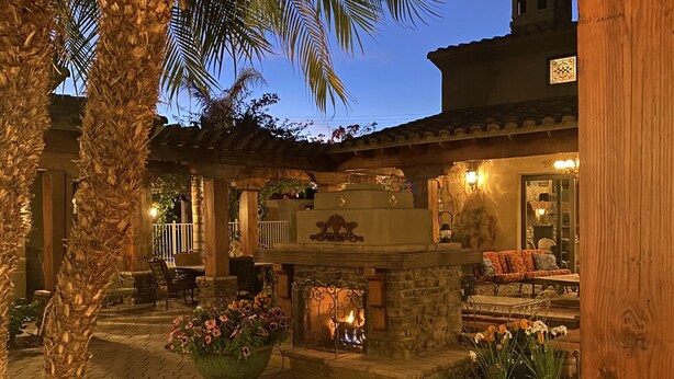 A courtyard with a stone fireplace, outdoor seating, and a palm tree. -  Heated resort pool , jacuzzi, out door sound system, secluded courtyard.<br> (Scottsdale)
