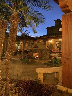 A courtyard with a stone fireplace, outdoor seating, and a palm tree. -  Heated resort pool, jacuzzi, outdoor sound system, secluded courtyard (Scottsdale)