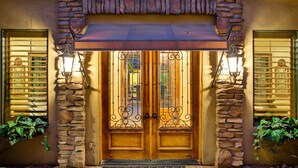 A double wooden door with a metal gate, flanked by stone walls and two windows with blinds. -  Heated resort pool , jacuzzi, out door sound system, secluded courtyard.<br> (Scottsdale)