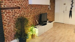 A living room with a brick wall, a white cabinet, a television, and a door.