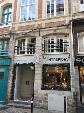 Una fachada con un letrero que dice "LES INTREPIDES" y una puerta adornada con un adorno floral.
