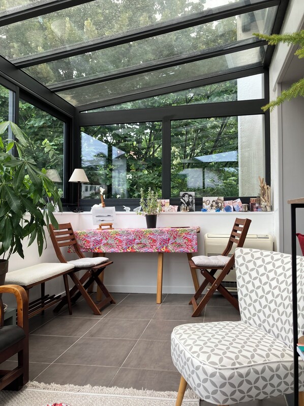 A conservatory with a table, chairs, and a potted plant.