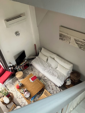 A living room with a sofa, a TV, a coffee table, and a staircase.