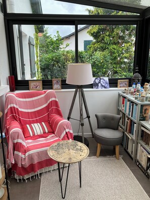 A cozy room with a red striped chair, a small round table, a floor lamp, and a bookshelf filled with books.