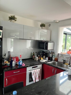 A modern kitchen with a gas stove, microwave, and red cabinets.