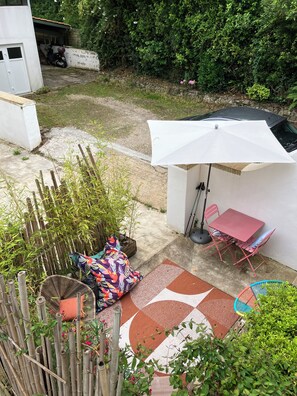 A patio area with a table and chairs, a white umbrella, and a bamboo fence.
