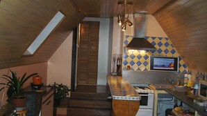 A kitchen with wooden cabinets, a stove, and a microwave. There is a window with a view of the outside.
