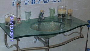 A bathroom with a glass sink, a mirror, and a mosaic tile backsplash.