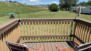 A wooden deck with two metal chairs and a small table.