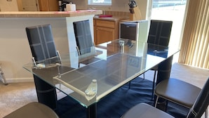 A modern kitchen with wooden cabinets, a glass dining table, and black leather chairs.