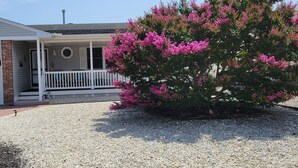 A house with a porch, a gravel driveway, and a flowering bush. - Relaxing Getaway on the Island.  (Cape May)