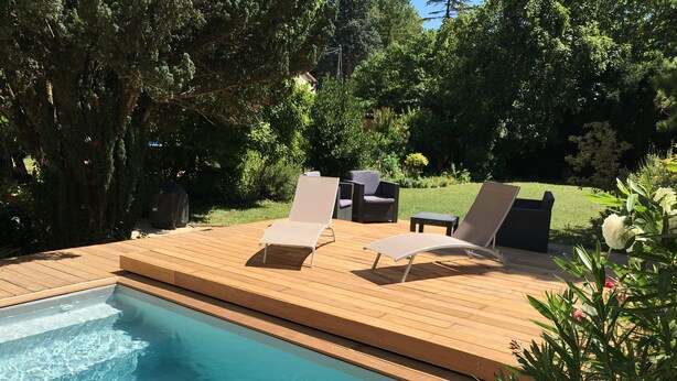 En pool med ett trädäck och solstolar.