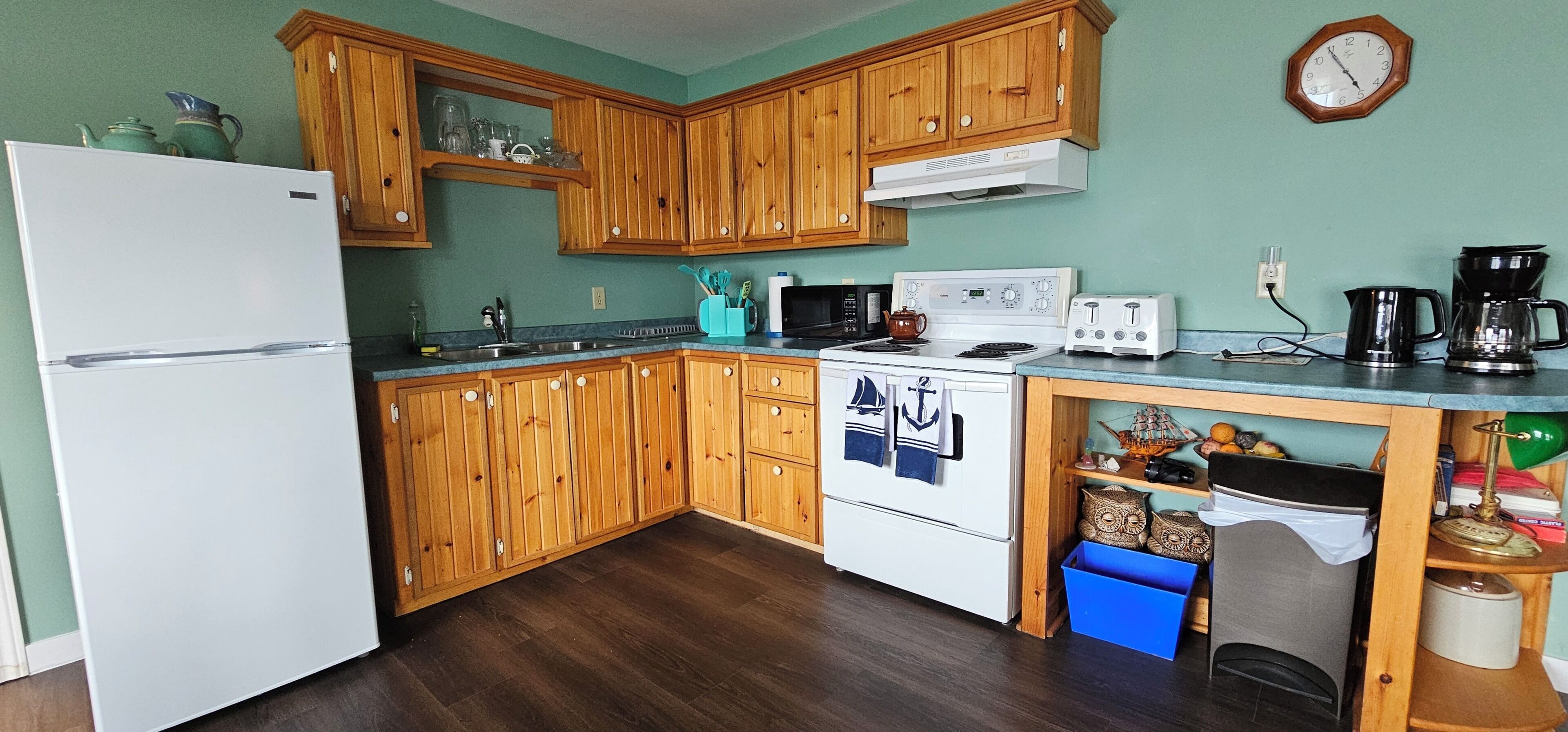 A kitchen with wooden cabinets, a white refrigerator, a stove, a microwave, and a coffee maker.