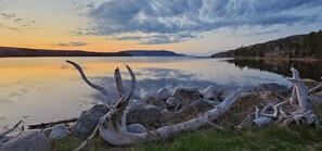 A calm lake with a sunset, surrounded by rocks and driftwood. - St. Ann's Motel (South Haven)