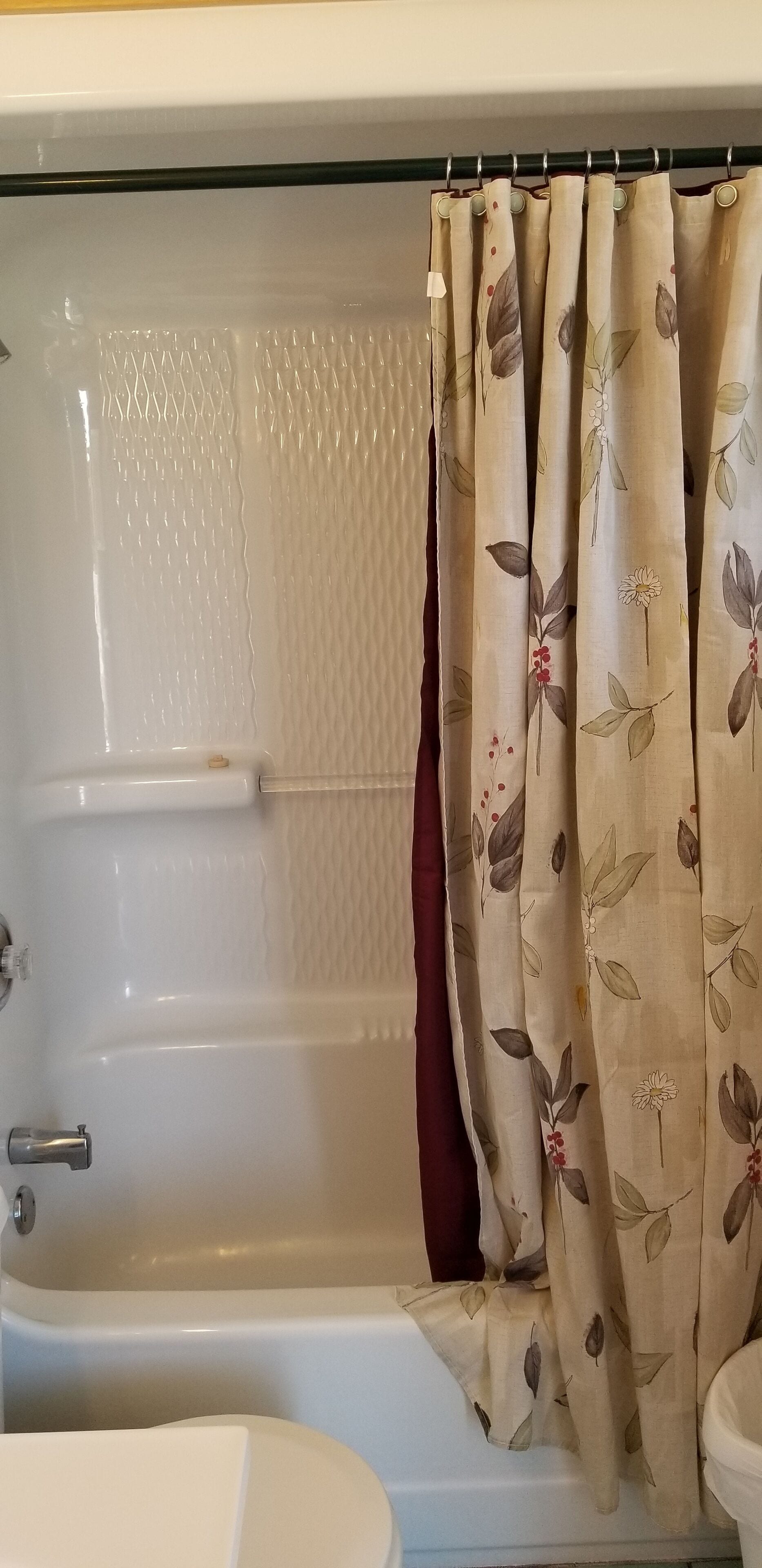 Un baño con bañera, inodoro y cortina de ducha.