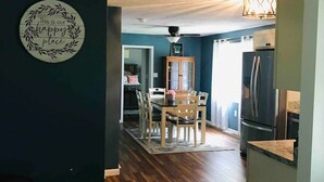 A modern kitchen with a dark blue wall, a wooden dining table, and a black refrigerator. - Peaceful Retreat near Ohiopyle and Fallingwater HOT TUB (Mill Run)