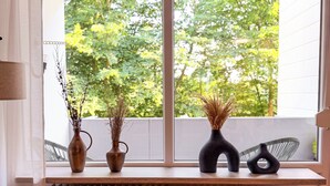 Ein Zimmer mit Fenster, Heizkörper, Stuhl und zwei Vasen auf der Fensterbank.
