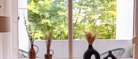 Una habitación con ventana, un radiador, una silla y dos jarrones en el alféizar.