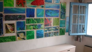 A room with a white cabinet and a wall decorated with colorful fish paintings. - Typical house in Saint Sauveur (L'Île-d'Yeu)