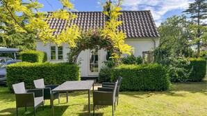 A house with a tiled roof, a garden with a table and chairs, and a hedge. - Stunning home in Allinge with WiFi (Allinge)