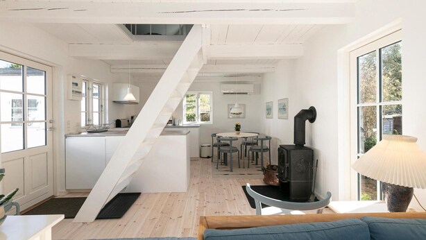 A modern kitchen with white cabinets, a dining area with a round table and chairs, and a black wood-burning stove. - Stunning home in Allinge with WiFi (Allinge)