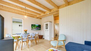Una sala de estar acogedora con vigas de madera, televisor, comedor con sillas y sofá.