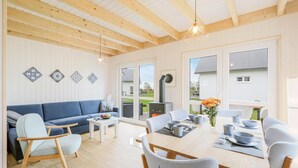 Un interior moderno con techo de madera, sofá azul, mesa de comedor con sillas y azulejos decorativos.